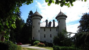 Een kasteel met twee torens, omringd door groen en een heldere lucht.