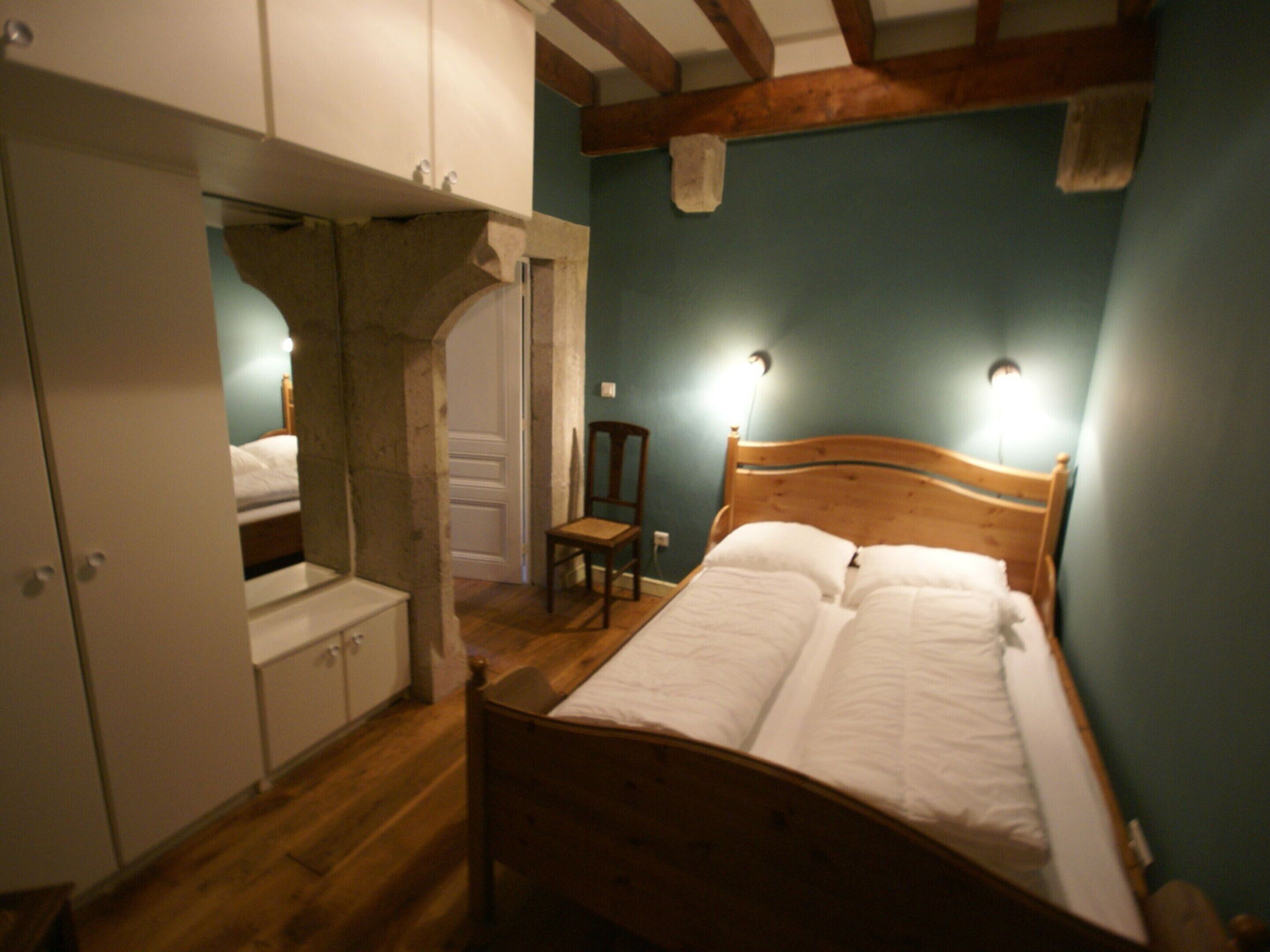 A bedroom with a wooden bed, a chair, and a wardrobe.