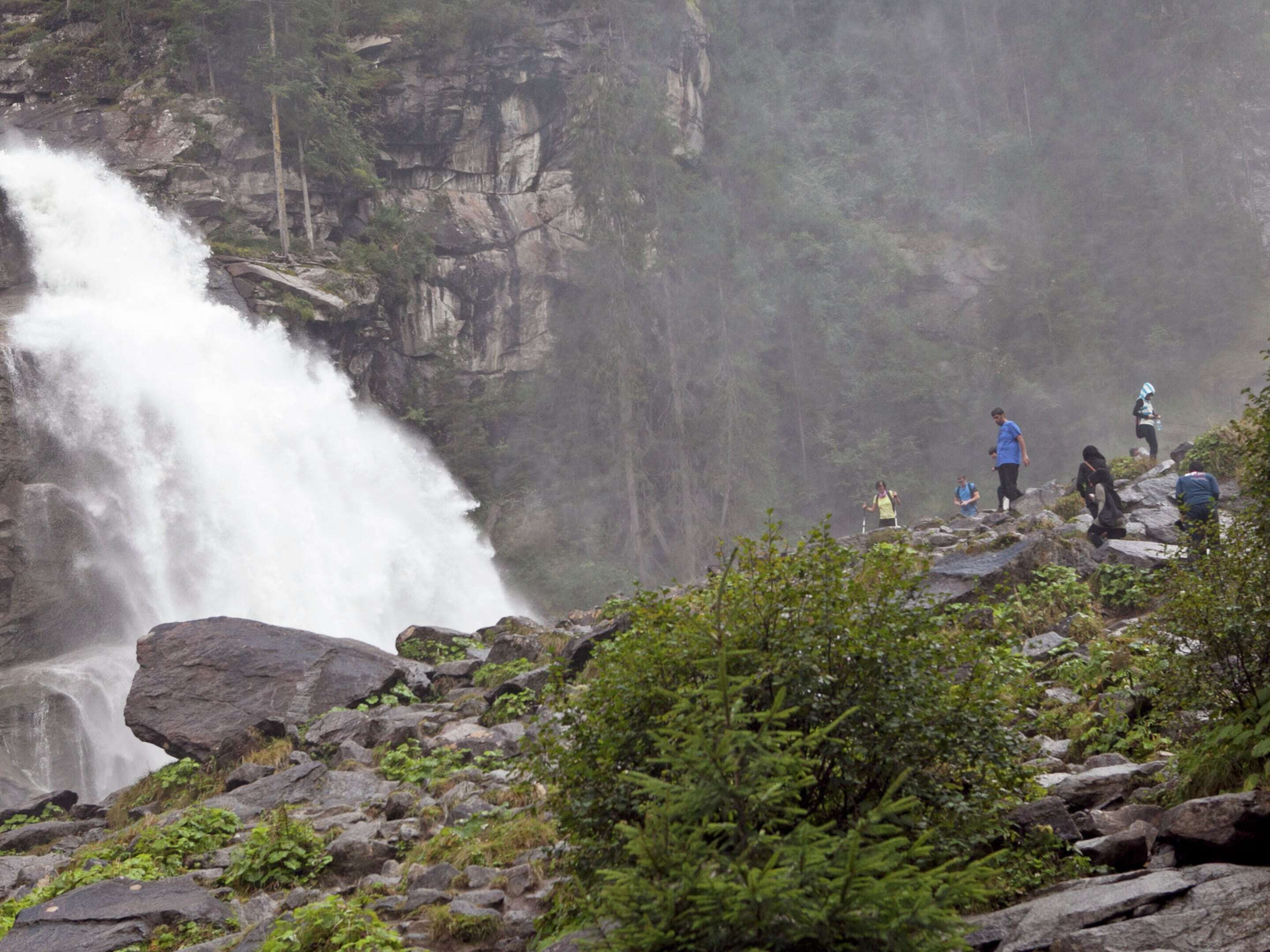 A waterfall cascading down a rocky cliff surrounded by lush greenery.