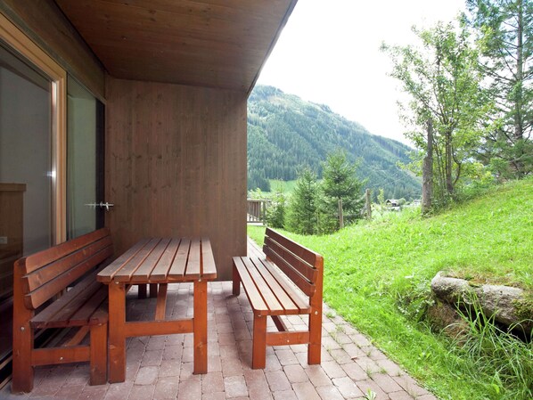 Un ensemble de banc et de table en bois, installé sur une terrasse en briques avec vue sur les montagnes.