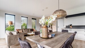Une cuisine moderne avec une table à manger en bois, des chaises foncées et un luminaire suspendu.