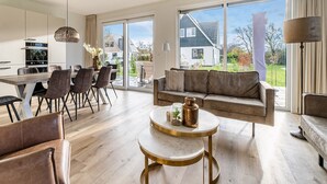 Un salon moderne comprenant un canapé, une table basse et un coin repas avec des chaises.