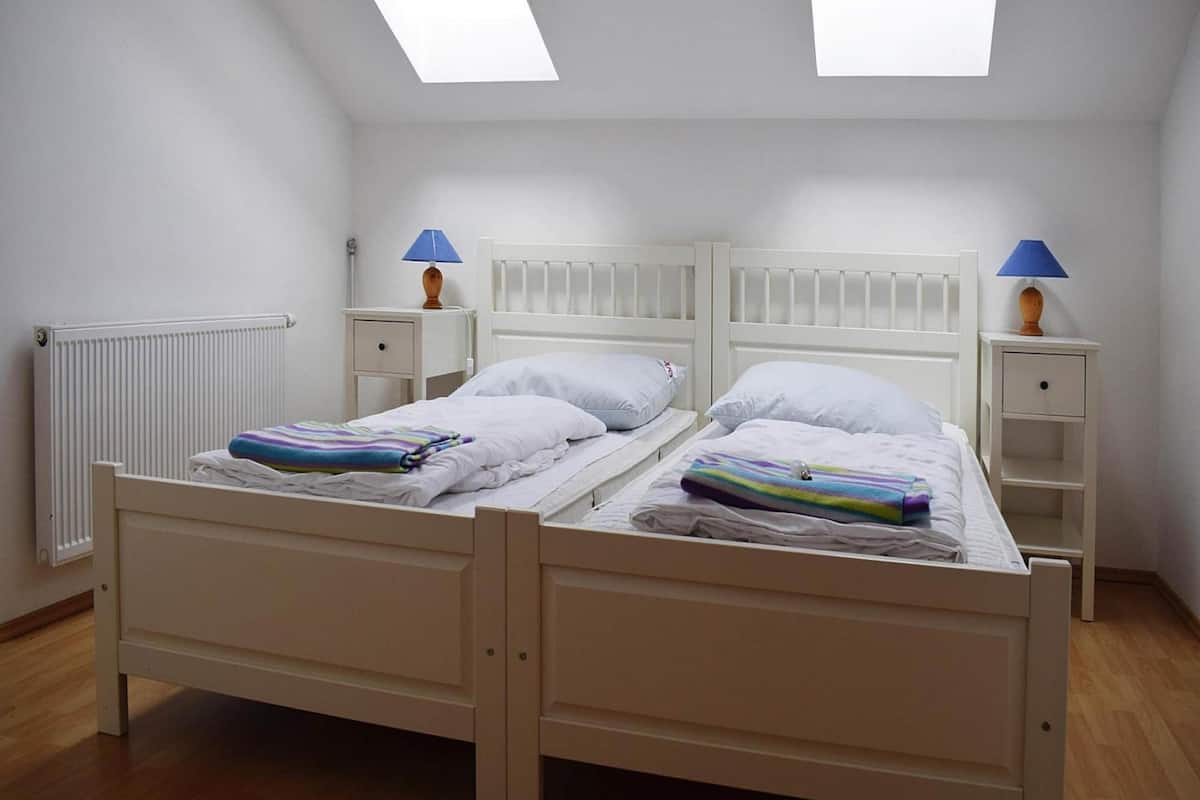 A twin room with two beds, a skylight, a radiator, and bedside tables with lamps.