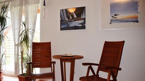 A room with two wooden chairs, a small round table, and a potted plant. There are two framed pictures on the wall. - Landhaus Amadeus, Radstadt (Radstadt)