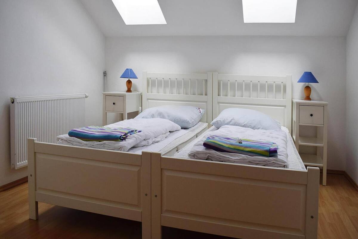 A twin room with two beds, a skylight, a radiator, and bedside lamps.