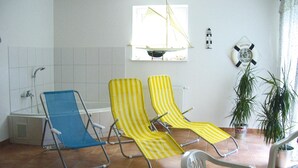 A room with two striped lounge chairs, a bathtub, a potted plant, and a life preserver decoration on the wall. - Landhaus Amadeus, Radstadt (Radstadt)