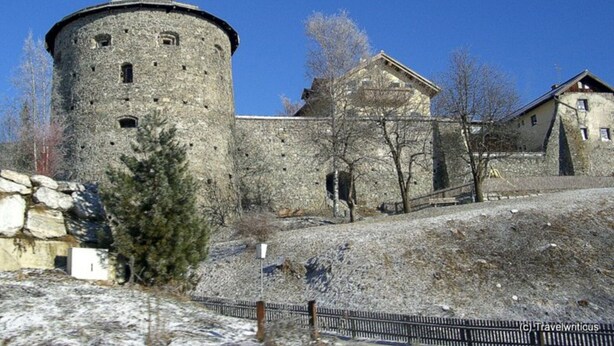 A historic stone building with a round tower, a flat-roofed structure, and a fenced area with sparse vegetation. - Landhaus Amadeus, Radstadt (Radstadt)