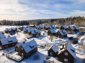 A cluster of wooden cabins with snow-covered roofs, surrounded by a snowy landscape and trees. - Semi-detached Houses, Turf House (Clausthal-Zellerfeld)