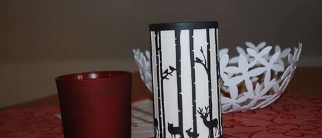 A red candle and a decorative candle holder with a forest and deer design.