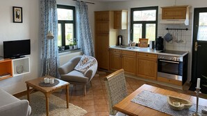 A compact living space with a kitchenette, a sofa, a TV, and a dining area. - Grosses Landhaus mit Swimmingpool in Dargun (Dargun)