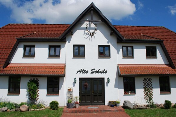 A two-story building with a red-tiled roof, a black front door, and the name "Alte Schule" above it. - Grosses Landhaus mit Swimmingpool in Dargun (Dargun)