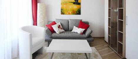 Una sala moderna con un sofá gris, una mesa de centro blanca y un cuadro en la pared.