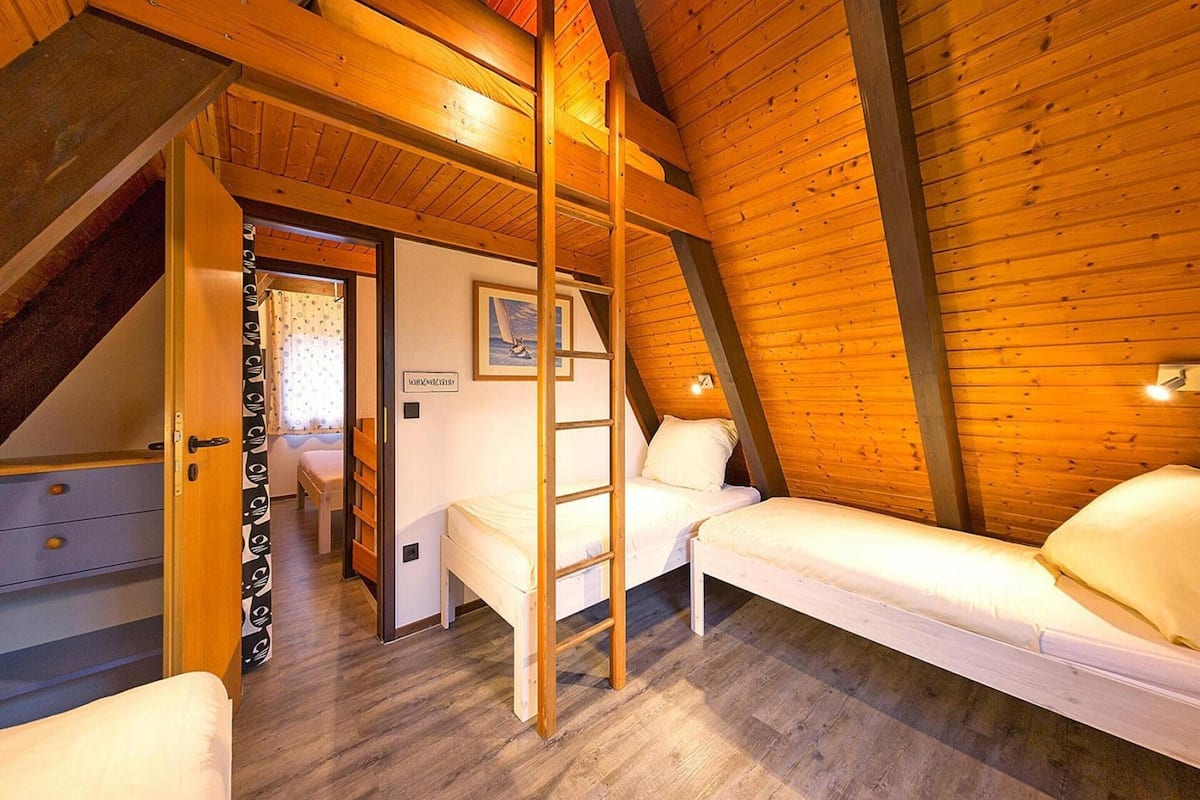 A cozy attic bedroom with a loft bed, a small desk, and a ladder.