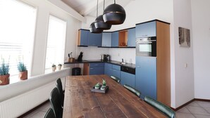 Eine moderne Küche mit blauen Schränken, einem Holzespeisetisch und Pendelleuchten.