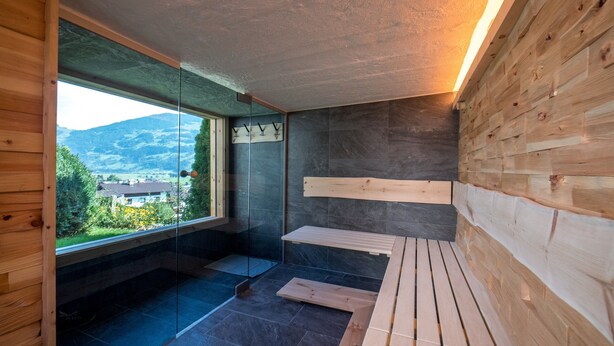 A modern bathroom with a glass shower enclosure, a wooden bench, and a view of the outdoors. - Holiday Home With Sauna (Fuegen)