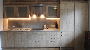 A modern kitchen with wooden cabinets, a stainless steel sink, and under-cabinet lighting. - Holiday Home With Sauna (Fuegen)