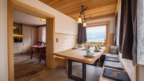 A cozy dining area with a wooden table, benches, and a view of the mountains. - Holiday Home With Sauna (Fuegen)