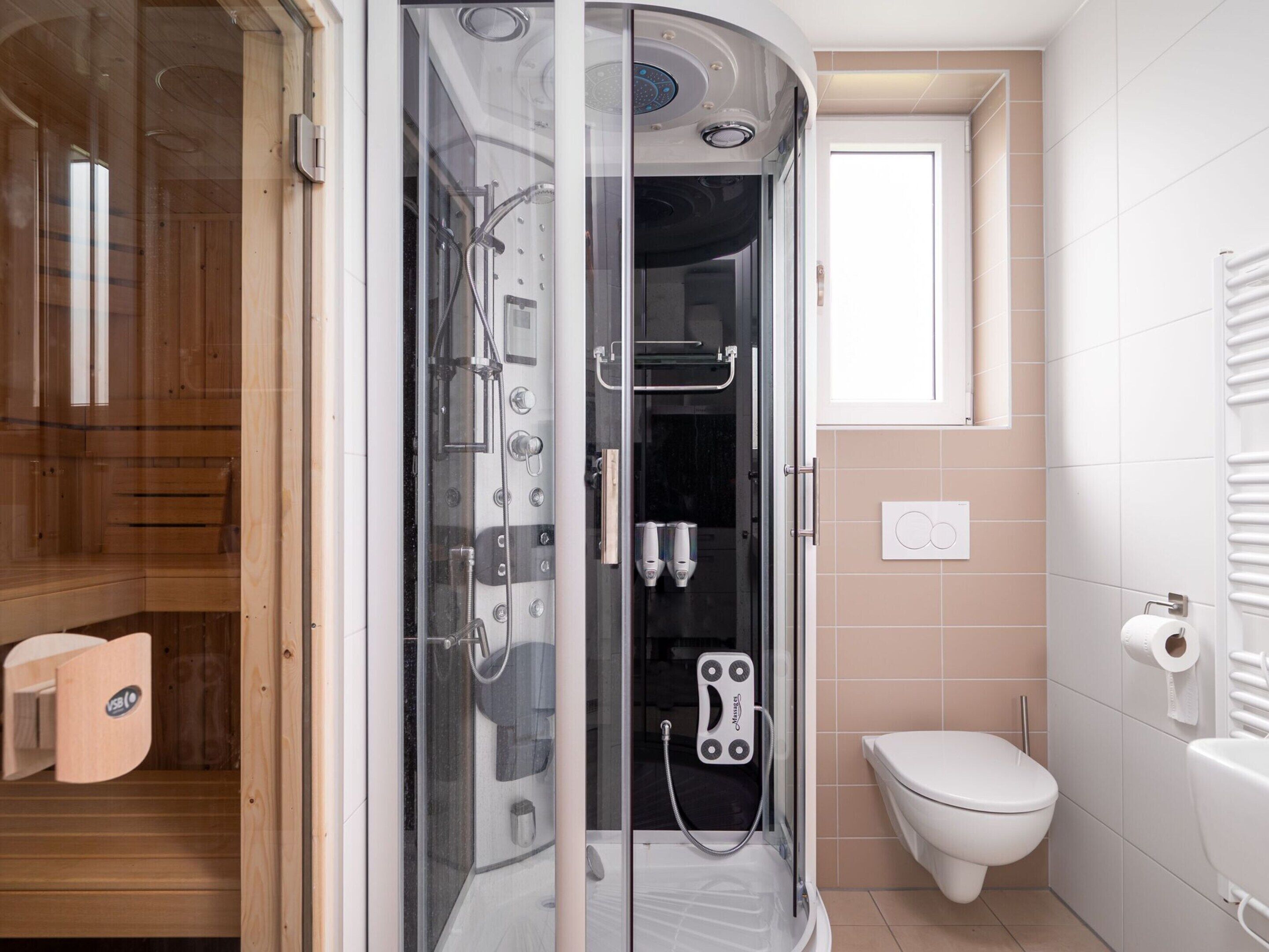 A modern bathroom with a glass-enclosed shower, a toilet, and a wooden cabinet.