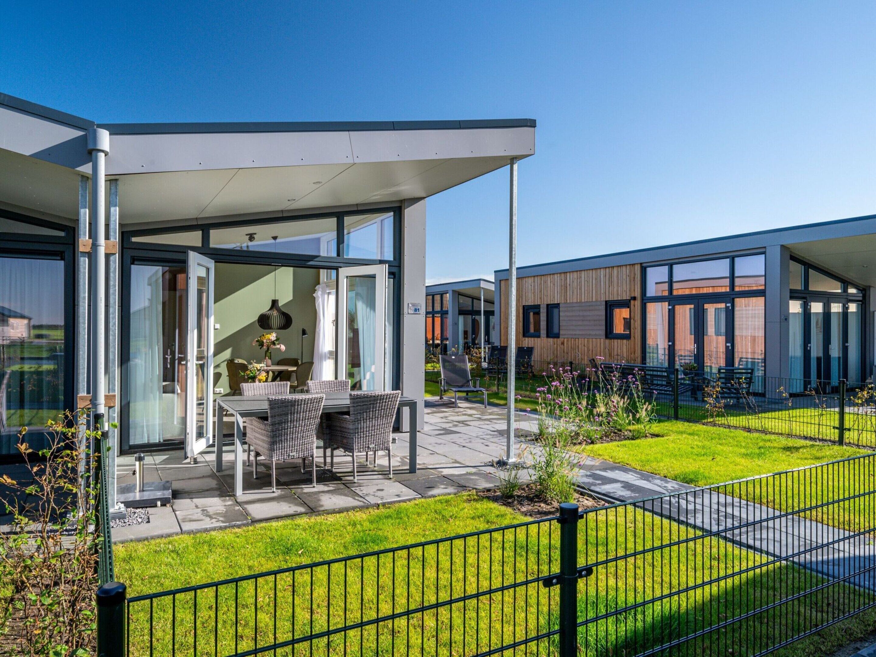 A modern building with a covered patio area, outdoor seating, and a well-maintained lawn.