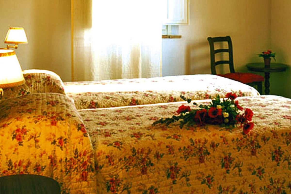 A room with a bed, a chair, a table, and a window with curtains.