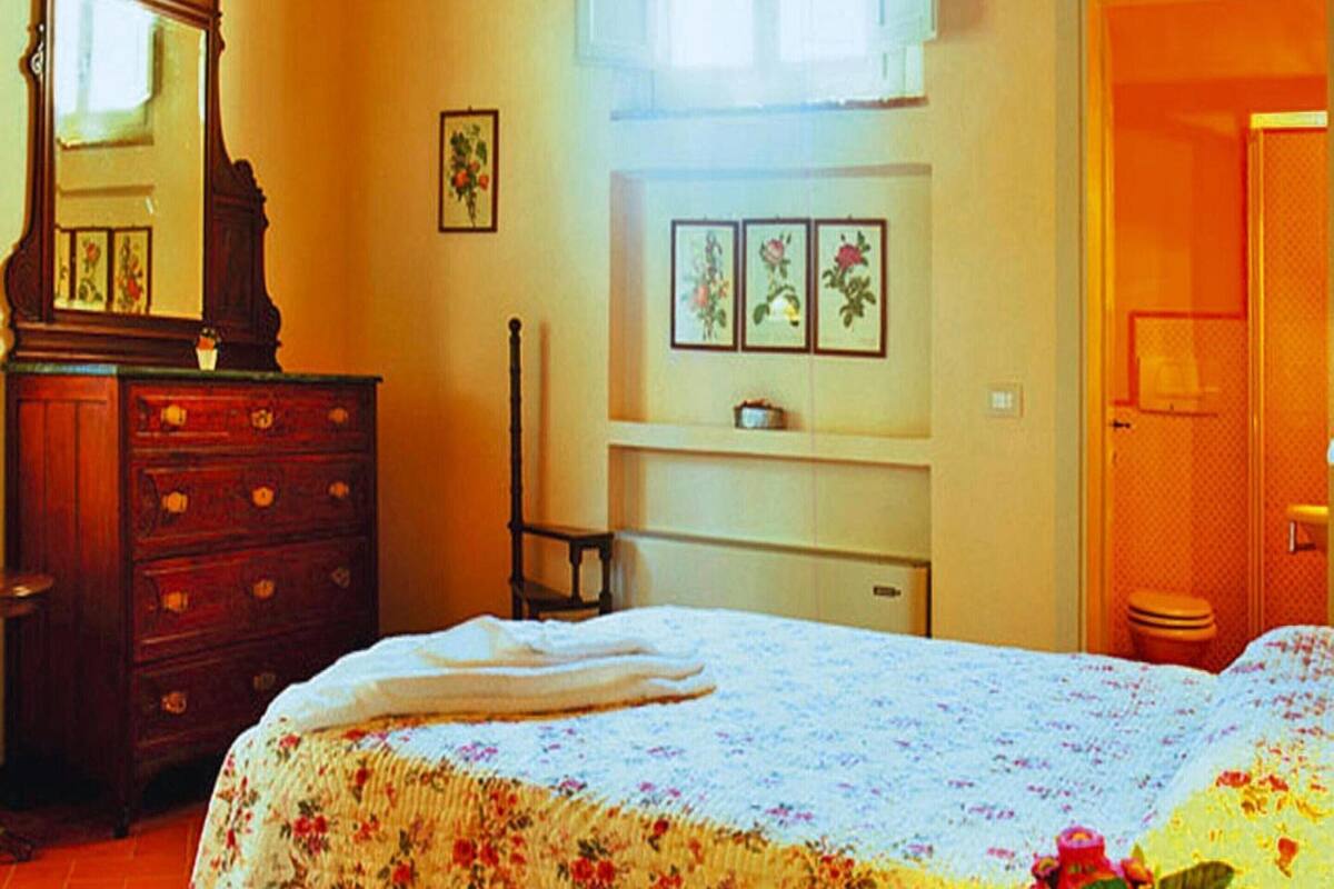 A bedroom with a bed, dresser, and a window.
