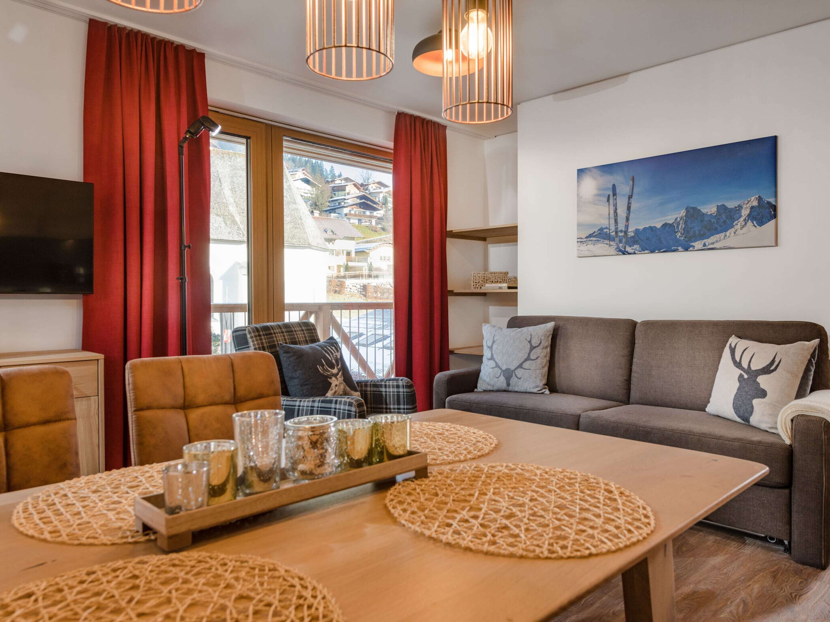 A cozy living room with a sofa, a dining table with placemats, a television, and a window with curtains.