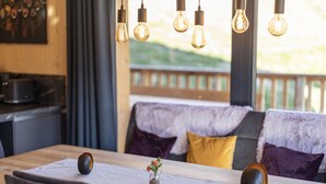 A dining area with a wooden table, chairs, and hanging light bulbs. - Gorgeous Chalet in Steinach am Brenner Near Ski Area (Steinach am Brenner)