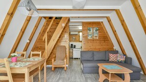 A cozy attic room with a wooden ceiling, a dining table with chairs, a sofa, and a small wooden table. - Holiday Homes, Kolobrzeg (Kolobrzeg)