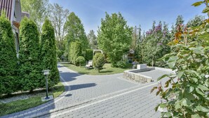 A paved pathway leading to a seating area with a pergola, surrounded by well-maintained greenery and trees. - Holiday Homes, Kolobrzeg (Kolobrzeg)