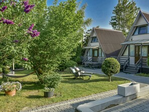 A modern house with a sloped roof, a patio with outdoor furniture, and a garden with trees and flowers. - Holiday Homes, Kolobrzeg (Kolobrzeg)