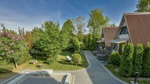 A modern building with a sloped roof and a paved driveway leading to a seating area with outdoor furniture. - Holiday Homes, Kolobrzeg (Kolobrzeg)