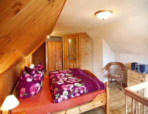 Un dormitorio con cama de madera, mesita de noche, lámpara, armario y silla.