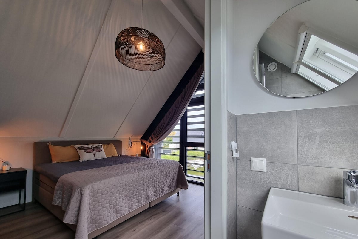 A bedroom with a bed, bedside table, and a hanging light fixture.
