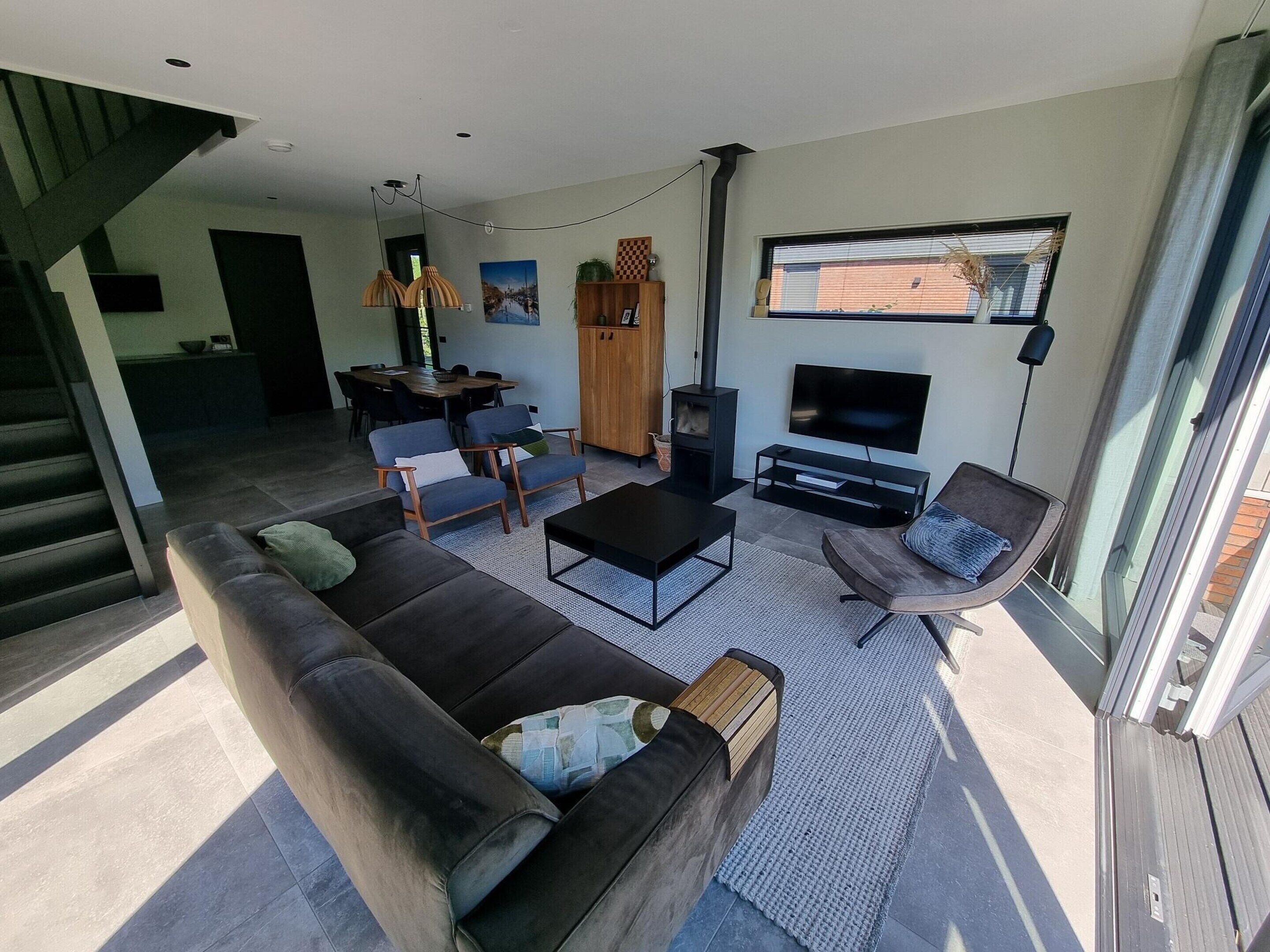 Una sala moderna con sofá, sillas, una mesa de centro, chimenea y televisor.
