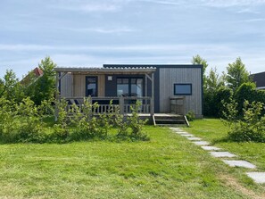 Et moderne, etplans hus med træterrasse og lille veranda.