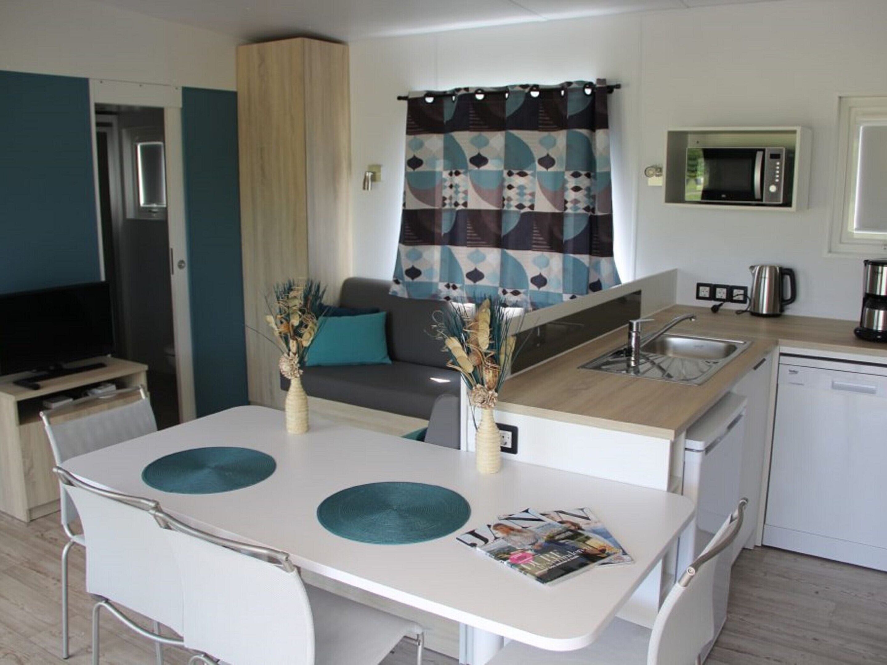 A compact kitchenette with a microwave, coffee maker, and sink. A small dining area with two chairs and a table is adjacent to the kitchenette.