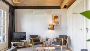 Un salon moderne comprenant un canapé, deux fauteuils, un téléviseur et une lampe sur pied.