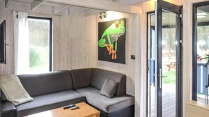 Ein modernes Wohnzimmer mit einem grauen Sofa, einem Holztisch und einem großen Fenster.