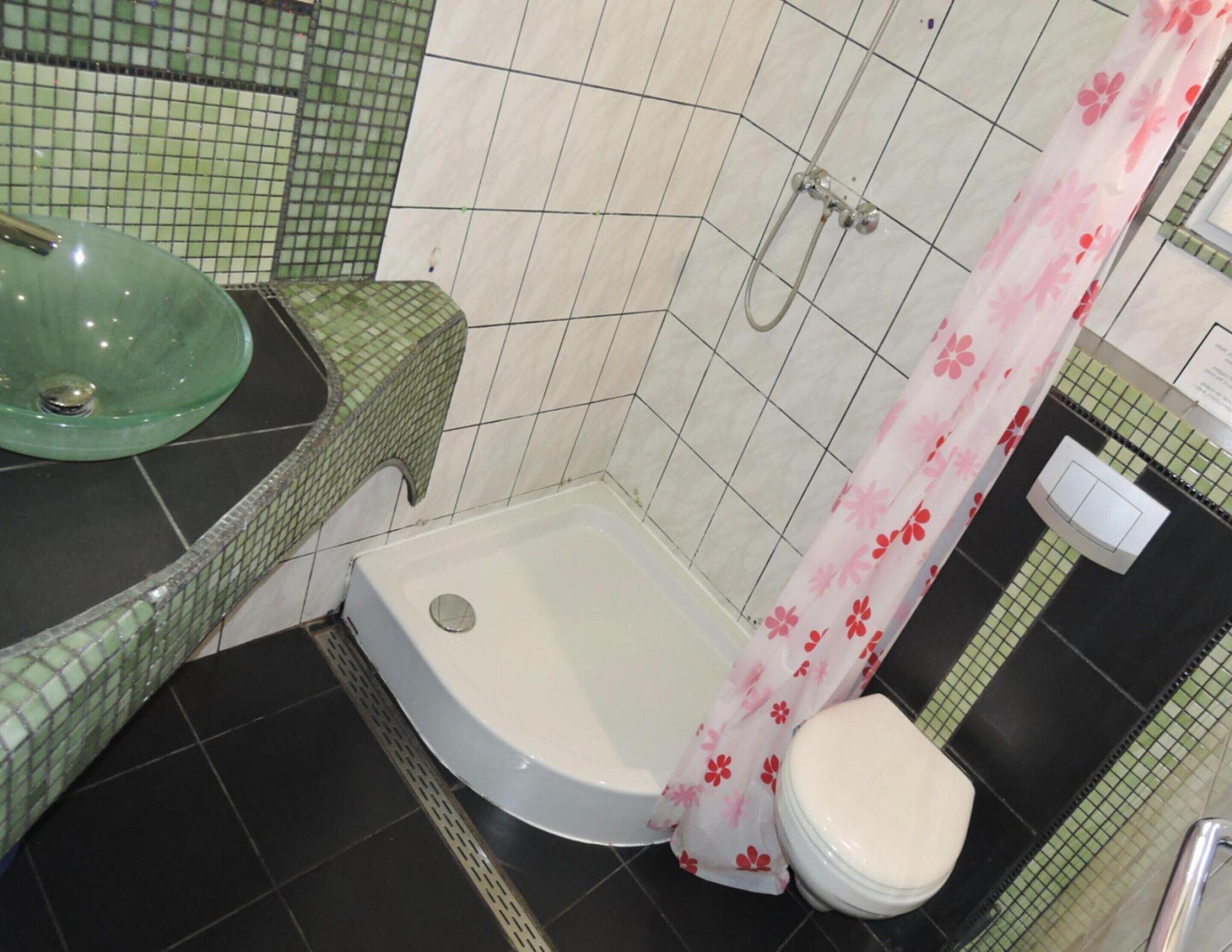 A bathroom with a shower, toilet, and sink.
