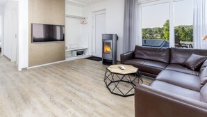 A modern living room with a fireplace, leather sofa, and a TV mounted on the wall. - Beautiful Holiday Home in Waxweiler With Pool (Waxweiler)