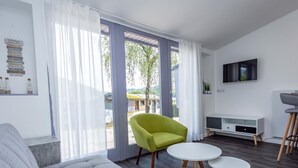 A modern living room with a grey sofa, a green armchair, and two white round tables. - Beautiful Holiday Home in Waxweiler With Pool (Waxweiler)