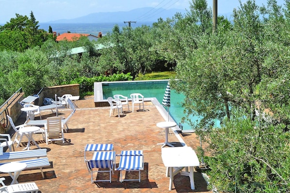 A rooftop pool area with lounge chairs and tables, surrounded by greenery and overlooking a mountainous landscape. - Appartements Villa Morosi, Lamporecchio (Lamporecchio)