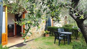 Ένας εξωτερικός χώρος με έναν τοίχο από πέτρα, μια γλάστρα με φυτό και ένα τραπέζι με καρέκλες.