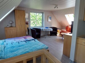 Ein gemütliches Schlafzimmer im Dachgeschoss mit einem Bett, einem Schreibtisch, einem Stuhl und einem Fenster.