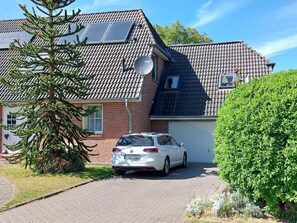 Ein Haus mit einem Auto auf der Auffahrt, Solaranlagen auf dem Dach und einer Satellitenschüssel.