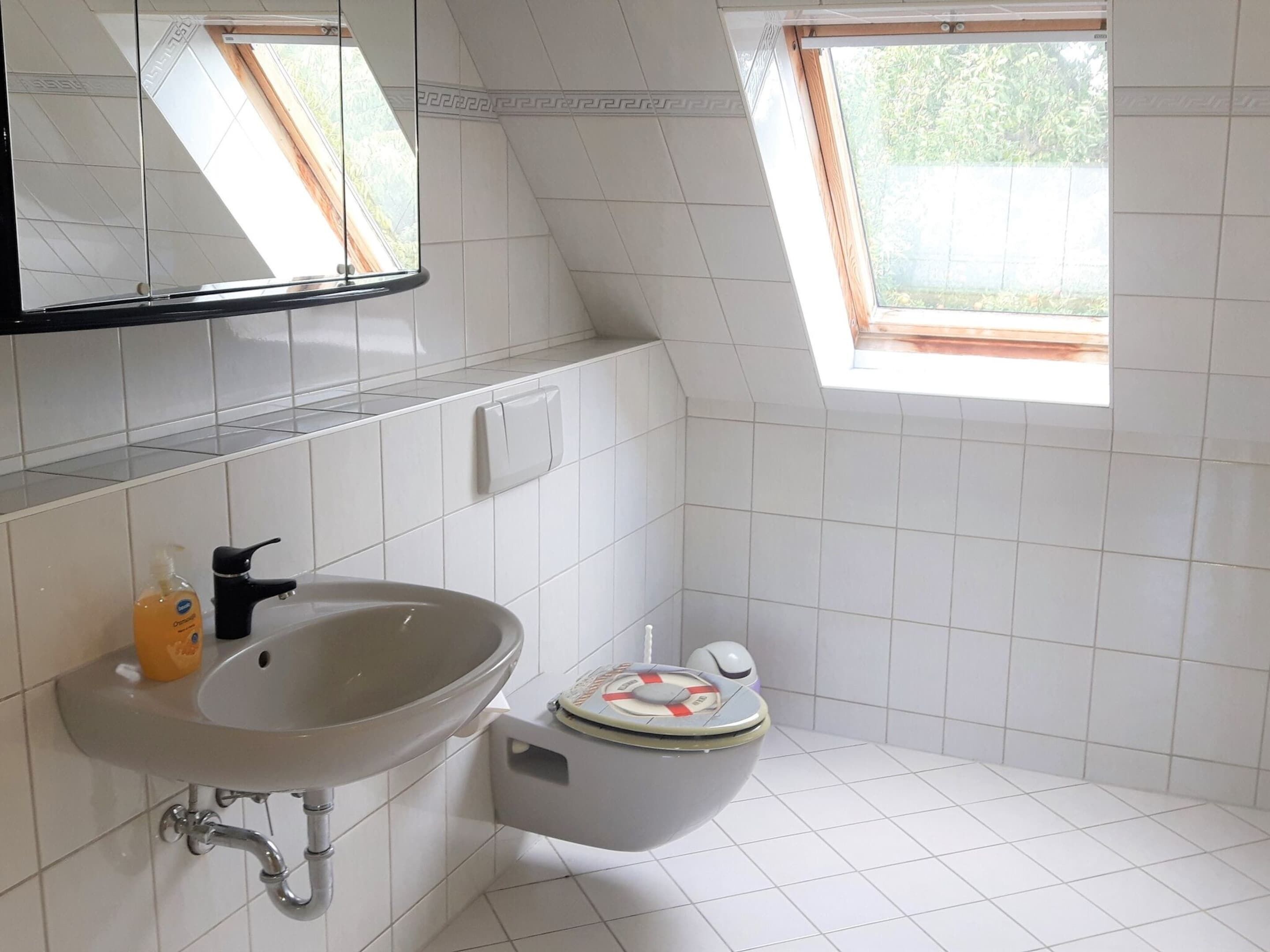 Un baño pequeño y moderno con un lavamanos blanco, un inodoro y una ventana.
