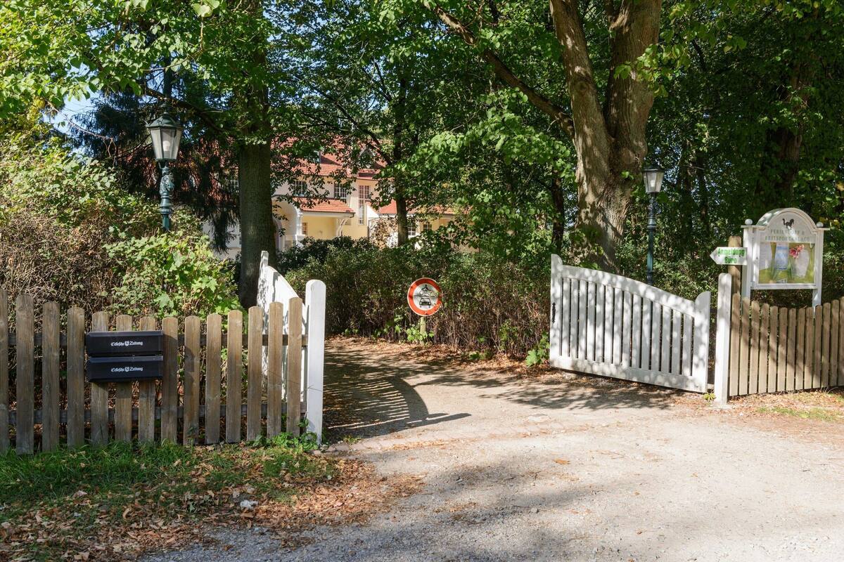 Une entrée fermée par un portail et une clôture en bois, un panneau indiquant l’interdiction d’accès et un poteau indicateur avec des informations sur les directions.