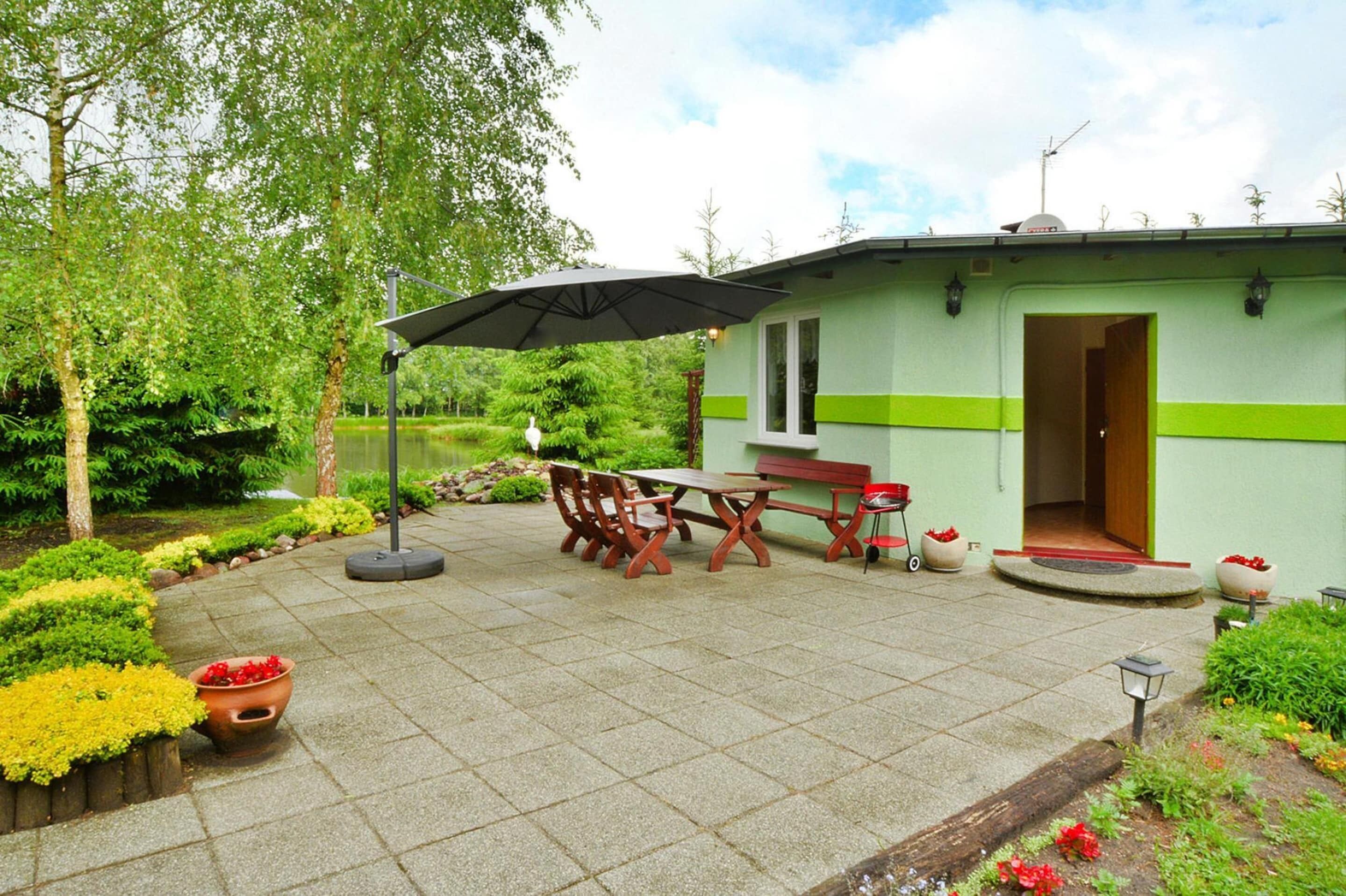 A patio area with a table and chairs, a bench, and a small garden with potted plants.