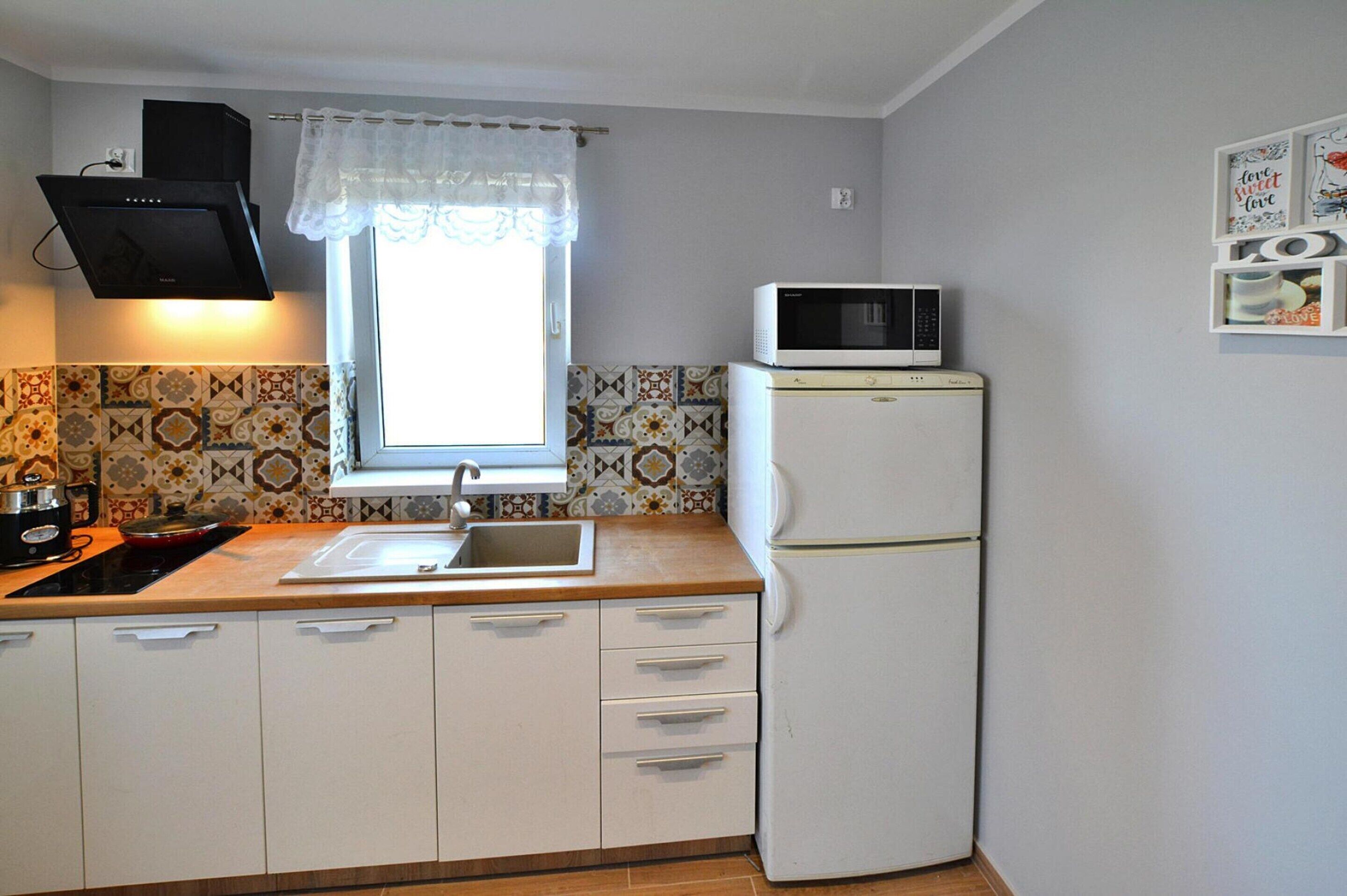 Une cuisine compacte équipée d’un évier, d’une cuisinière, d’un four à micro-ondes et d’un réfrigérateur.