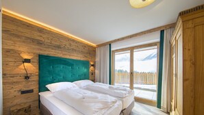 Ein Schlafzimmer mit einem Holz-Kopfteil, einem großen Fenster mit Blick auf Berge und einem Holzschrank.